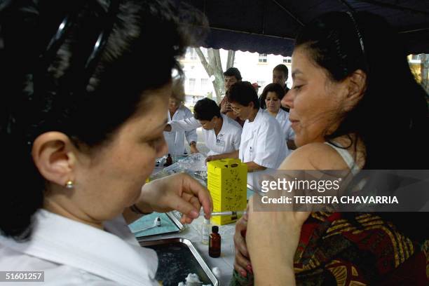 Nurse of the San Juan of God hospital immunizes a woman 04 May 2001 at an immunization stand in the Merced park, San Jose, Costa Rica, which country...
