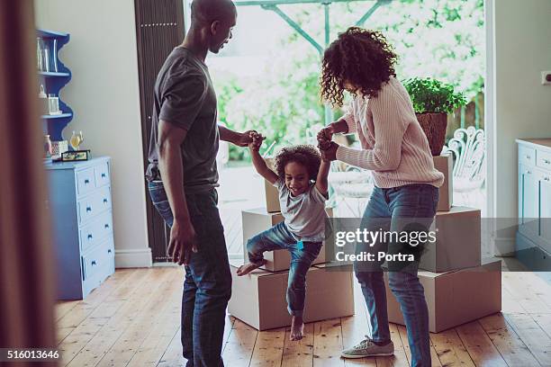 playful parents holding son's hands in new house - young family at home stock pictures, royalty-free photos & images