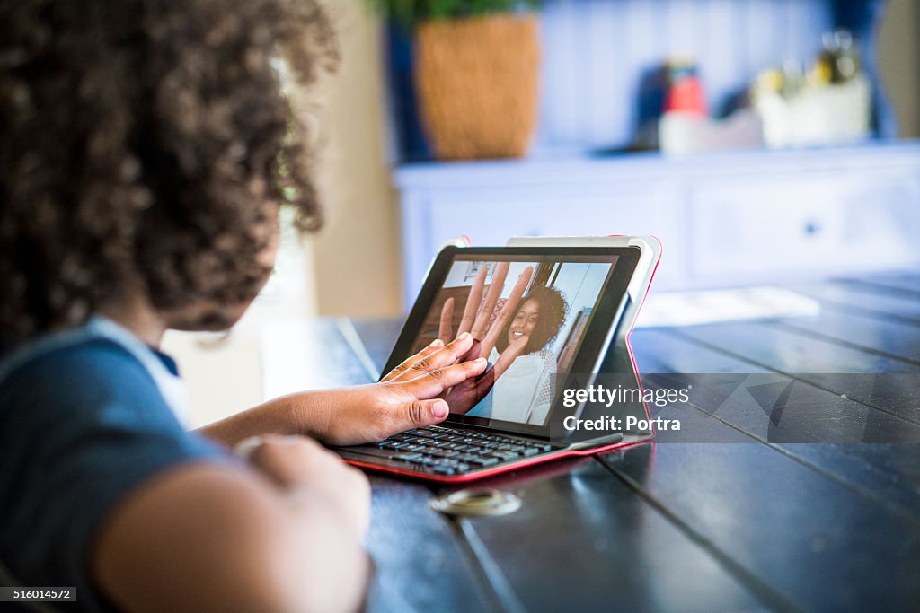 Girl video conferencing with mother on digital tablet