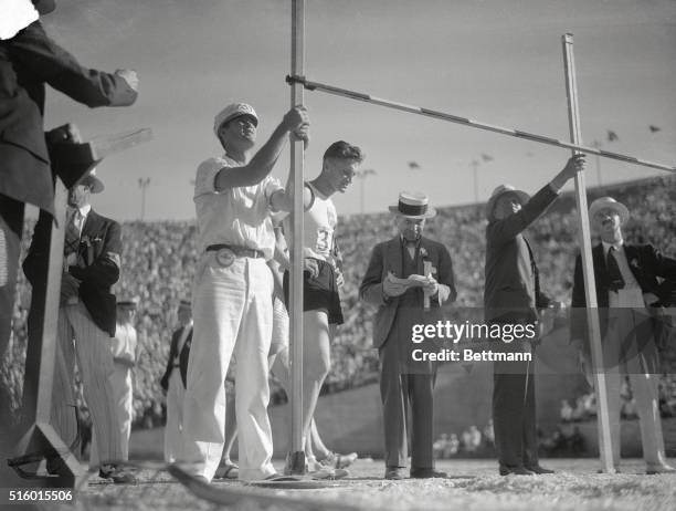 As he watches the judges measure his distance in the high jump event of the Decathlon, in today's Olympiad program. Dimsa, second from left.