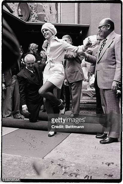Actress Ali MacGraw seems to be doing a dance as she puts her whole weight onto one foot while having her footprints and handprints permanently...
