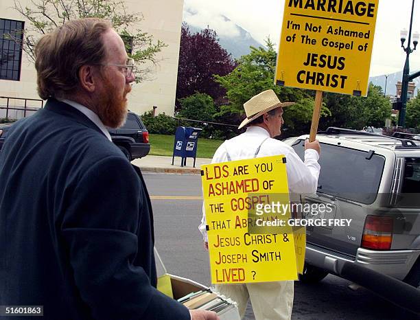 Utah polygamist Tom Green pauses to read the sign of a supporter Gurnie Cook outside 4th District Court in Provo, Utah where the third day of Green's...