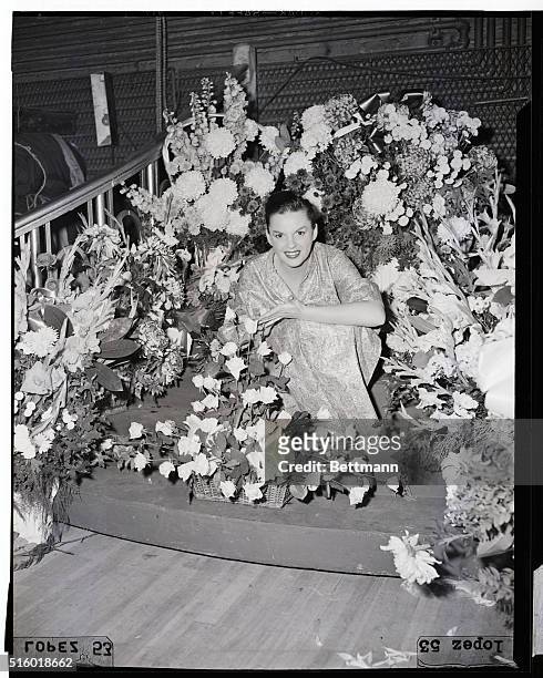 New York: Actress Judy Garland sits among some of the many baskets of flowers she received with her opening of a two-a-day vaudeville stand at...