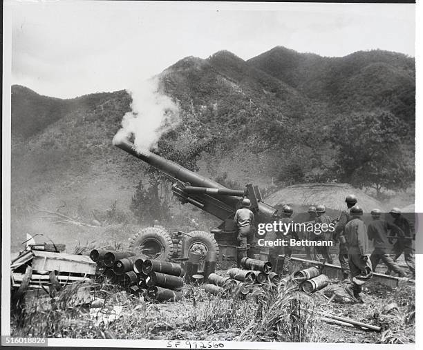 Korea: As smoke from the previous round curls about the hot barrel, crewmen of this U.S. Eight-inch Howitzer move quickly to ram another charge into...