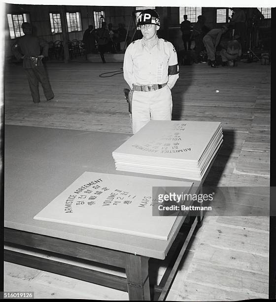 Lt. Martin H. Peterssen of Franklin Square, New York City, security officer at Panmunjom, stands guard next to two piles of documents marked...