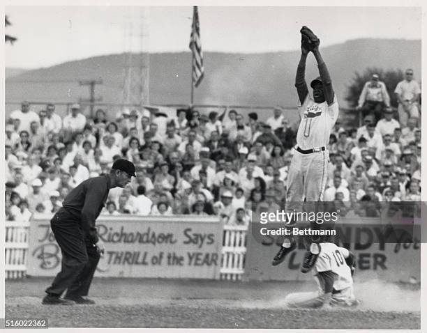 New Jersey Little Leaguer Wilbur Robinson leaps high for a ball thrown by catcher Bob Brush as Ferrell Dunham of the New Mexico team slides safely...