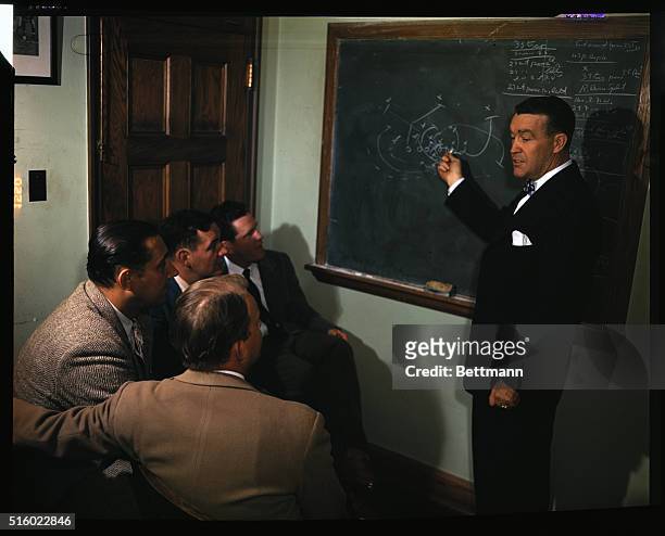 Picture shows Notre Dame football coach Frank Leahy and players studying plays for a game.