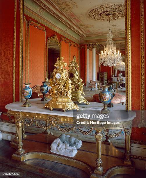 Table with ornate clock in front of a mirror in the drawing room, Brodsworth Hall, South Yorkshire, c2000s. Brodsworth was designed for Charles...