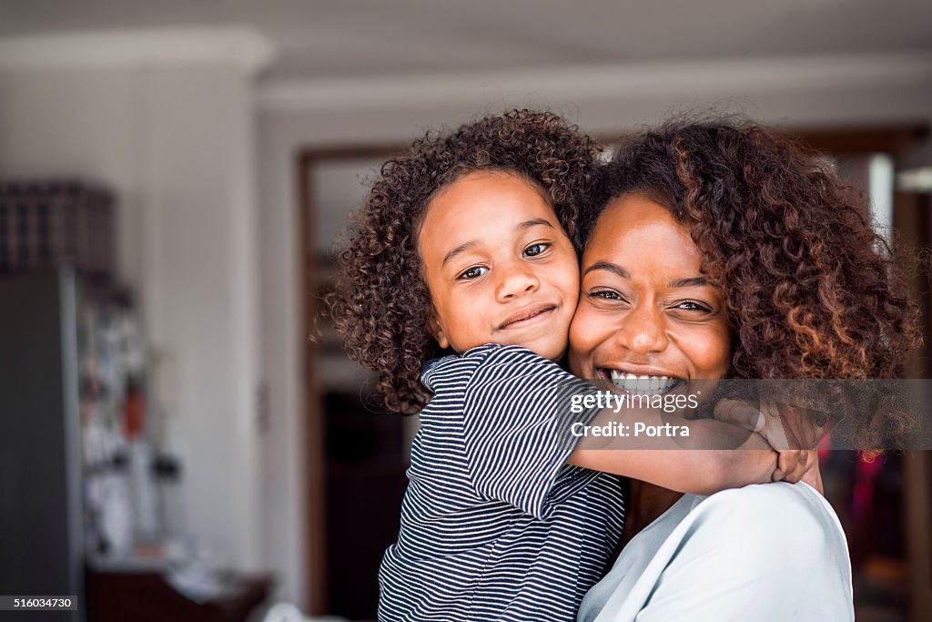 Happy mother and daughter embracing at home