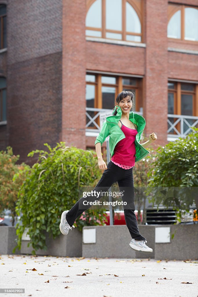 Mujer asiática corriendo sonriente de salto acceso al aire libre y