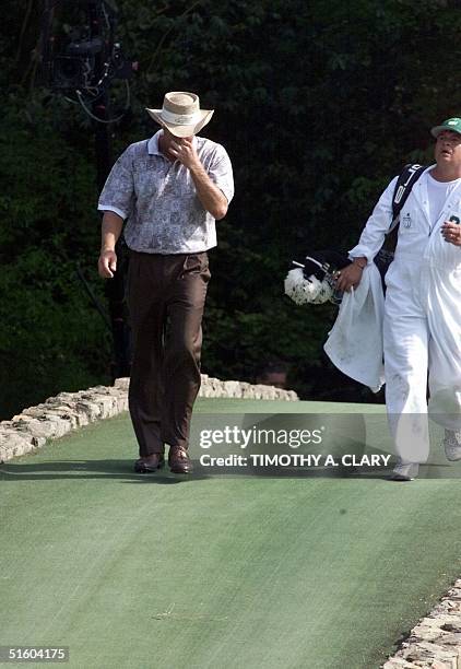 Greg Norman of Australia walks back across the bridge with his caddie Tony Navarro after not being able to find his lost ball on the 12th hole 10...