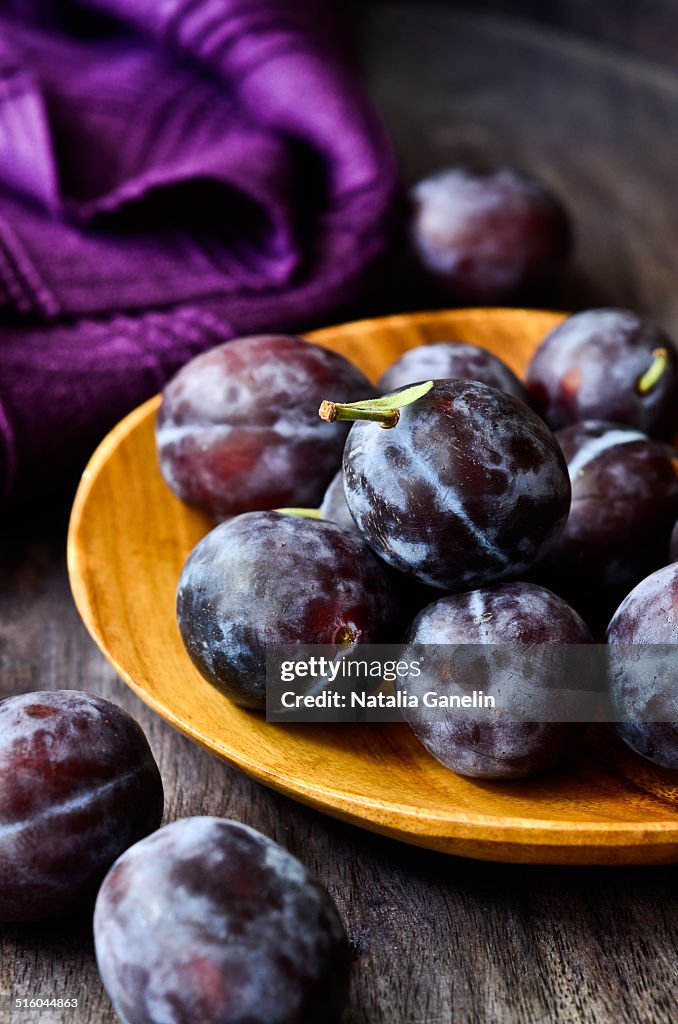 Fresh plums on a wooden plate