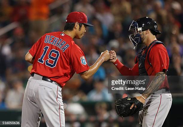 Koji Uehara of the Boston Red Sox leaves the game in the fifth inning and bumps fists with catcher Blake Swihart during the Spring Training Game on...