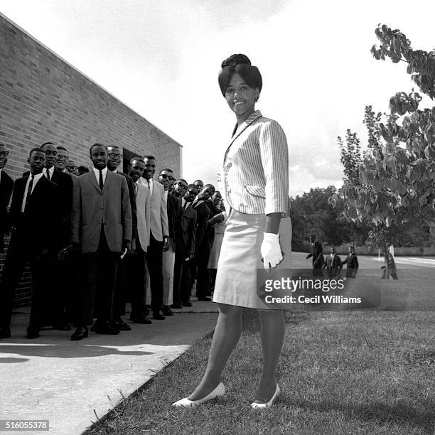 Portrait of an unidentified South Carolina State University student as she poses on the grass before a yearbook photo session, watched by a line of...