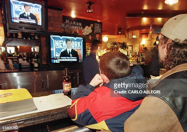 Jody Easton and his nine-year-old son Cody watch televisions inside Wayne Gretzky's restaurant called Wayne Gretzky's 16 April 1999 in Toronto as...