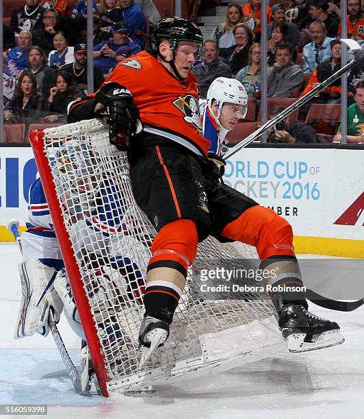Corey Perry of the Anaheim Ducks falls back onto the net as Antti Raanta of the New York Rangers looks on from inside the net during the game on...