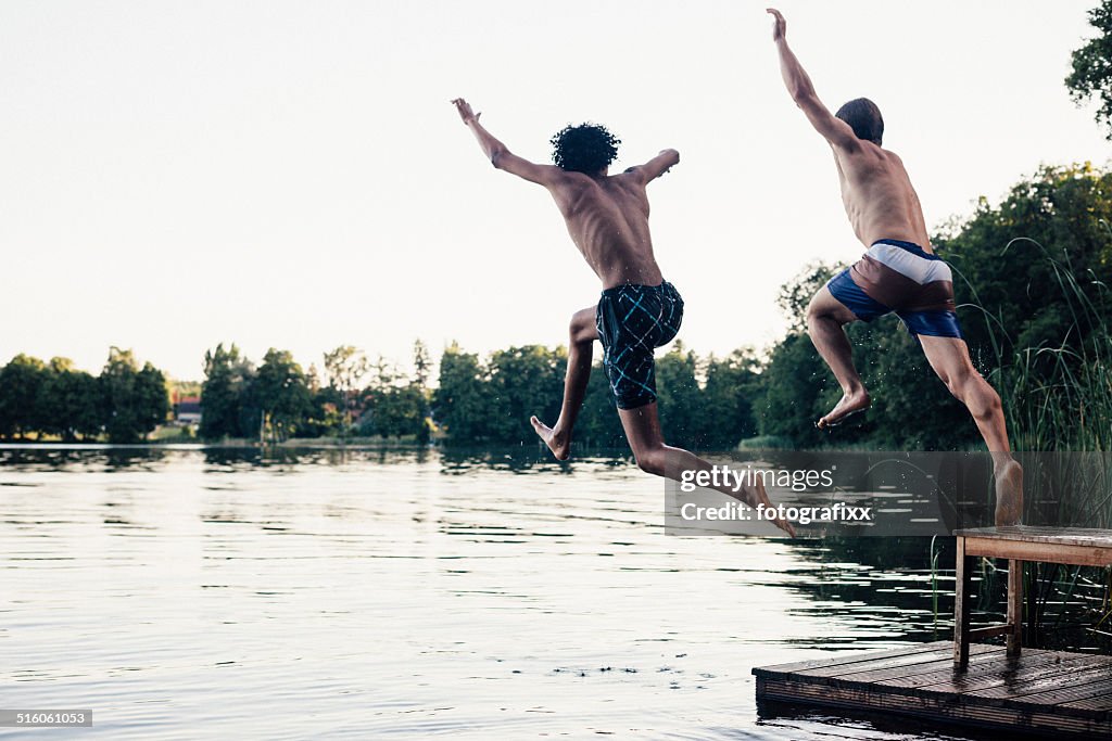Carefree summer day: teenagers jumping into a lake