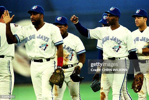 Toronto Blue Jay Devon White and his teammates celebrate late 16 October 1993, their victory against the Philadelphia Phillies 8-5 in game one of the...