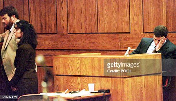 John Bobbitt waits while Lorena Bobbitt and her attorney James Lowe talk with the judge during the second day of her trial 11 January 1994. Lorena...
