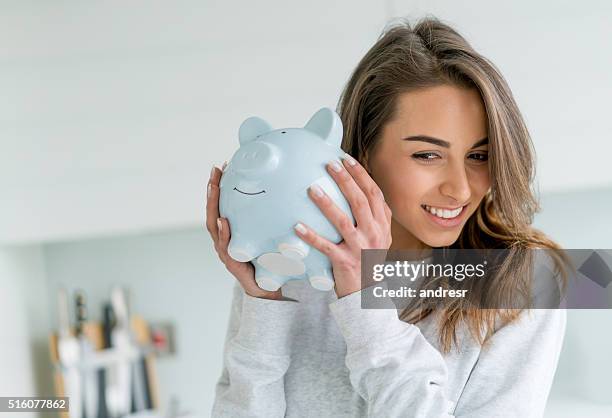 happy woman saving money in a piggybank - saving imagens e fotografias de stock