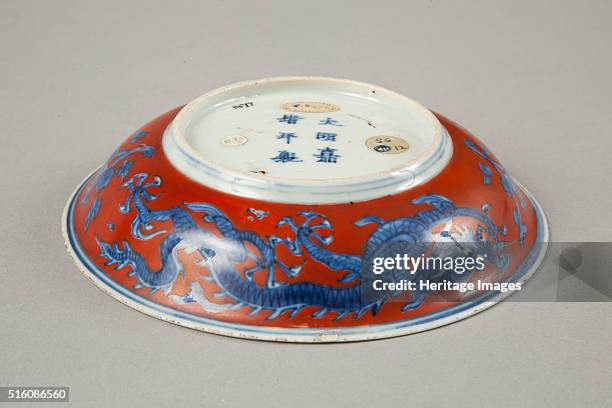 Polychrome saucer with slightly outturned rim, Jiajing . The piece is decorated in underglaze blue with a phoenix and stork and long-life character...