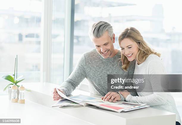 couple looking at the newspaper at home - ad magazine stockfoto's en -beelden