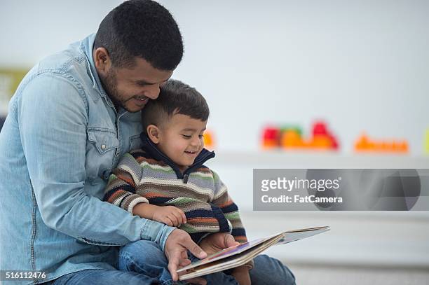 father and son reading a book together - indian baby boy stock pictures, royalty-free photos & images