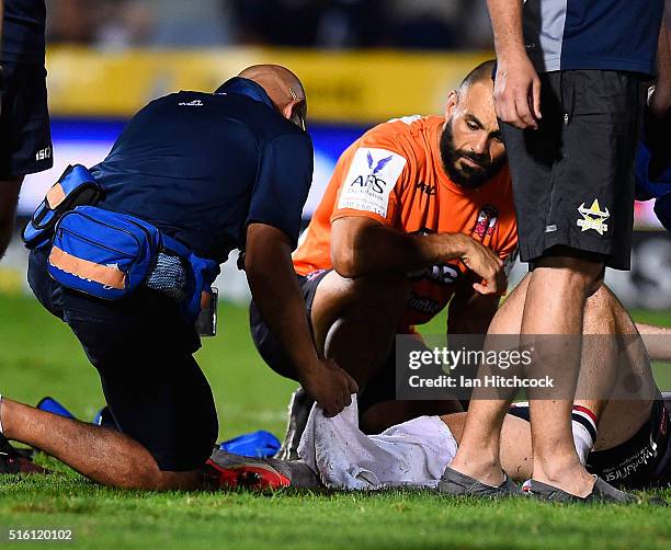 Ian Henderson of the Roosters has medical staff inspect his lower leg after being injured during the round three NRL match between the North...