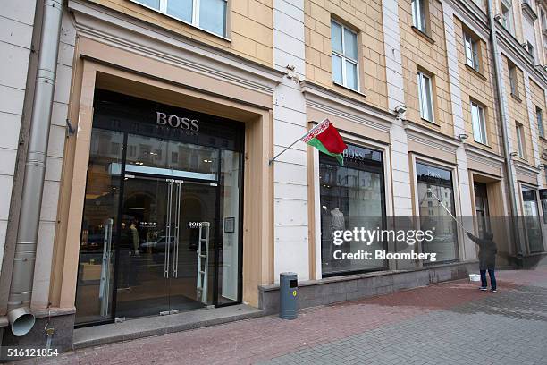 The national flag of Belarus flies outside a Hugo Boss AG luxury fashion store as a worker washes the display windows in Minsk, Belarus, on...