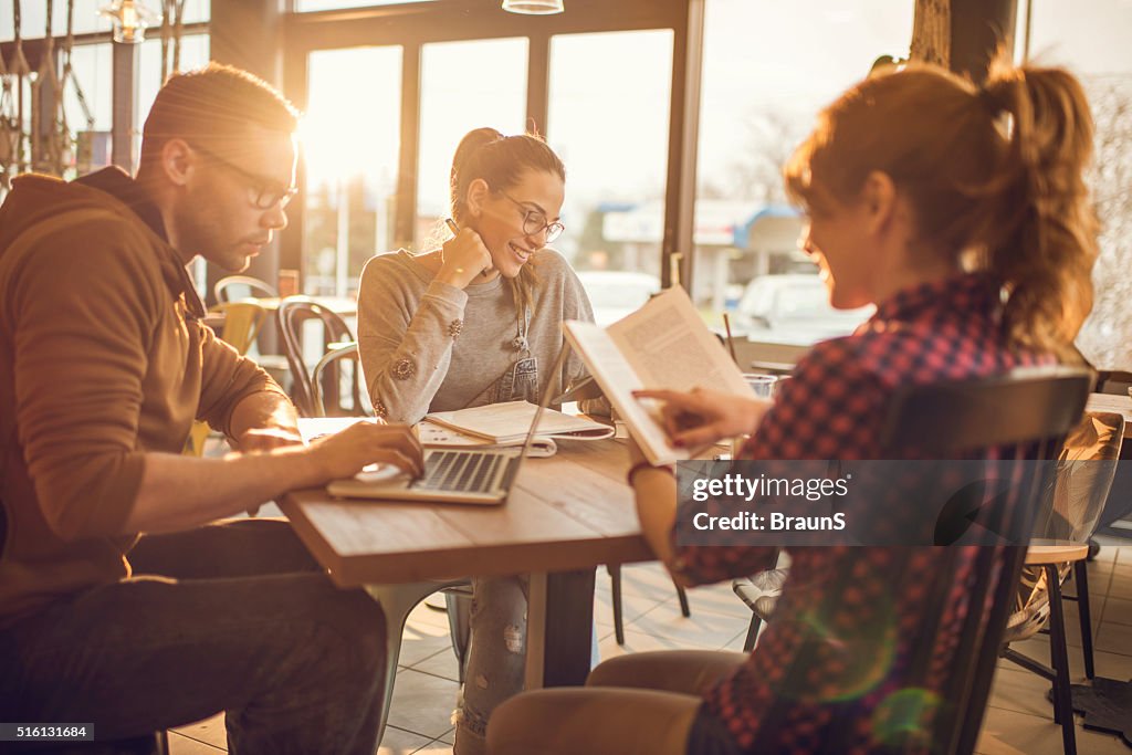 Group of multi-tasking college students in a cafe.