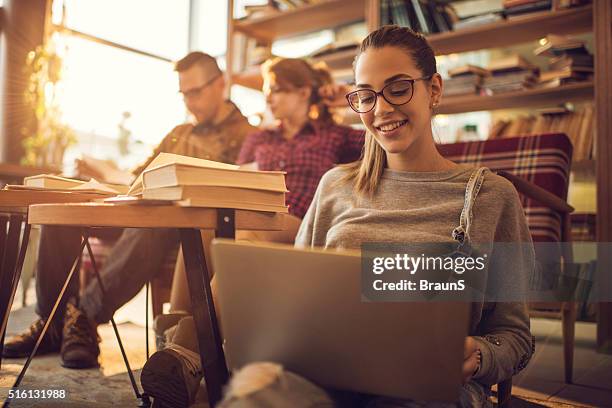 happy college student surfing the internet on her laptop. - happy students stockfoto's en -beelden