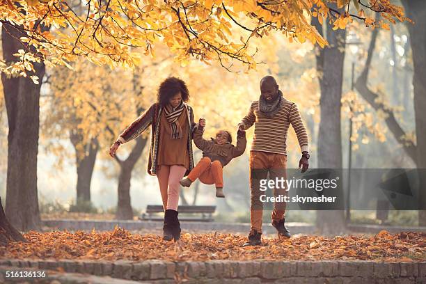 african american family walking and having fun in autumn park. - young leafs stockfoto's en -beelden
