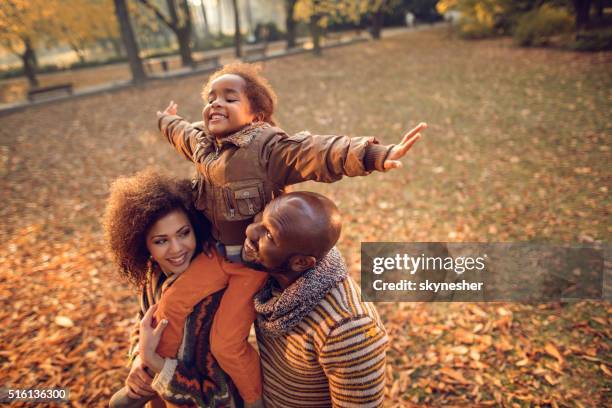 playful african american little girl having fun with parents outdoors. - herfst stockfoto's en -beelden