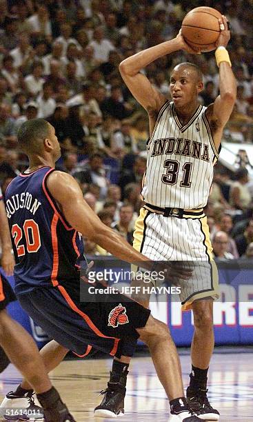 Reggie Miller of the Indiana Pacers looks to make a pass as Allan Houston of the New York Knicks guards 09 June during the first half of game five of...