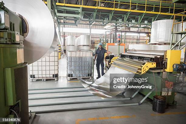 man standing by large roll of aluminium in factory - als stock pictures, royalty-free photos & images