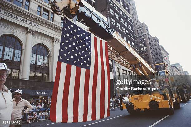 Large US flag is suspended from a mobile crane in a Labor Day parade in New York City, September 1982.