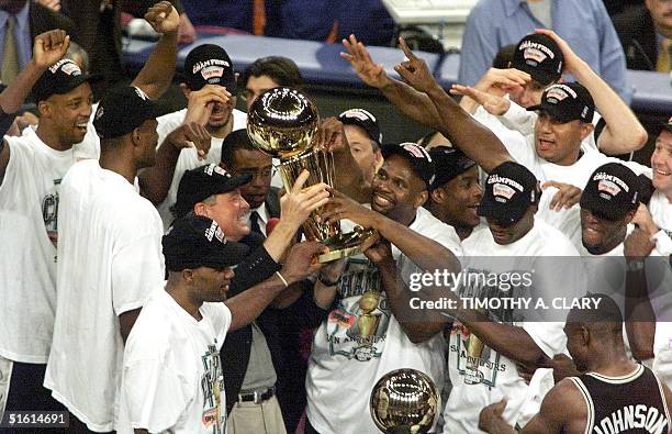 The San Antonio Spurs team gathers around the championship trophy 25 June after the Suprs won game five of the NBA Finals against the New York Knicks...