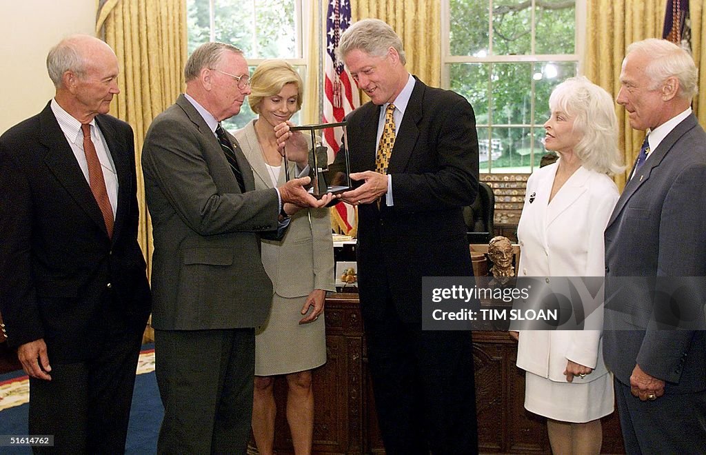 US President Bill Clinton (C) is presented a rock