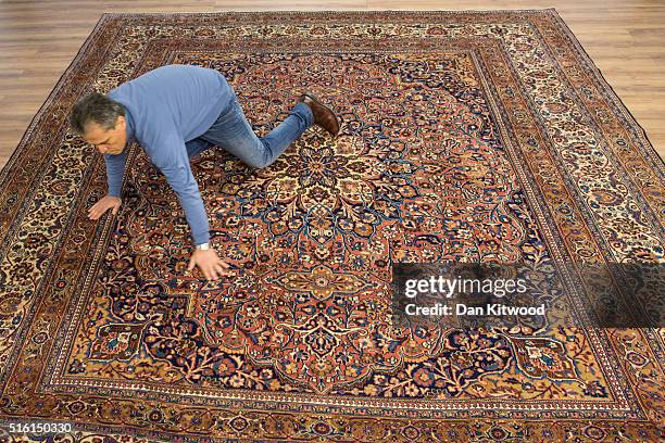 Managing director of the Oriental Rug Centre, Jalil Ahwazian flattens out an antique 'Dorokhsh' Persian Rug in the Oriental Rug Centre's main...