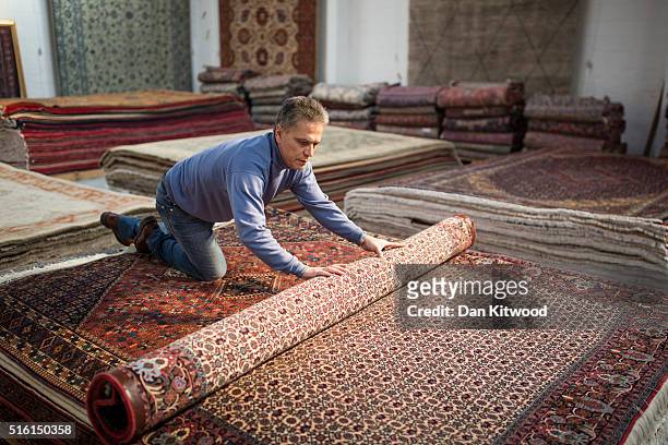 Managing director of the Oriental Rug Centre, Jalil Ahwazian rolls a Persian 'Bidjar' rug in the Oriental Rug Centre's main warehouse on March 17,...