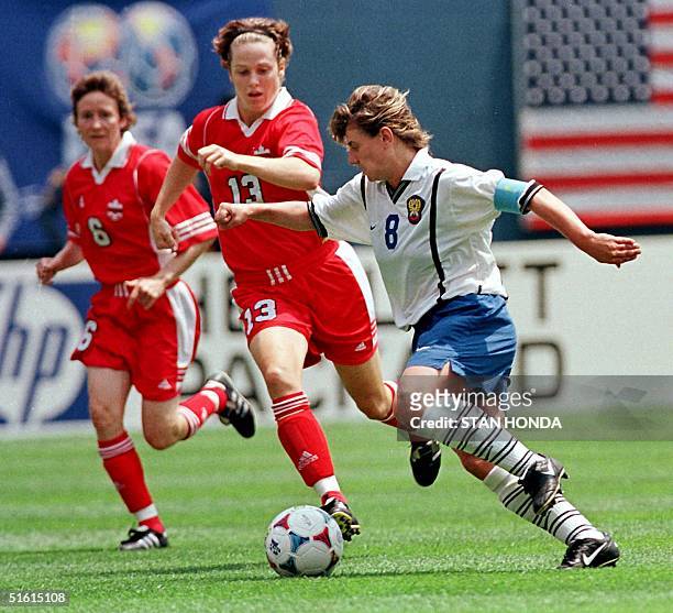 Irina Grigorieva of Russia pushes the ball past Canadians Amy Walsh and Geri Donnelly in the first half in the first round of Women's World Cup 26...