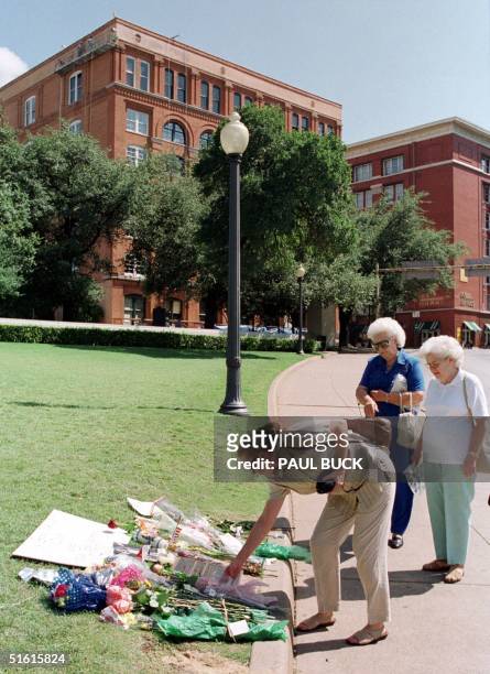 Tourists examine flowers and notes left at a makeshift memorial to John F. Kennedy Jr 20 July 1999 at Dealy Plaza in Dallas Texas, the place where...