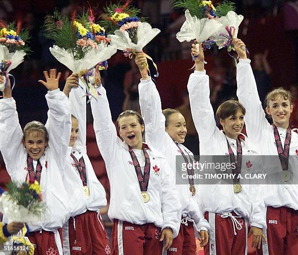 The Canadian women's gymnastic team holds up flowers after winning the gold medal in the team competition during the qualification round 24 July 1999...
