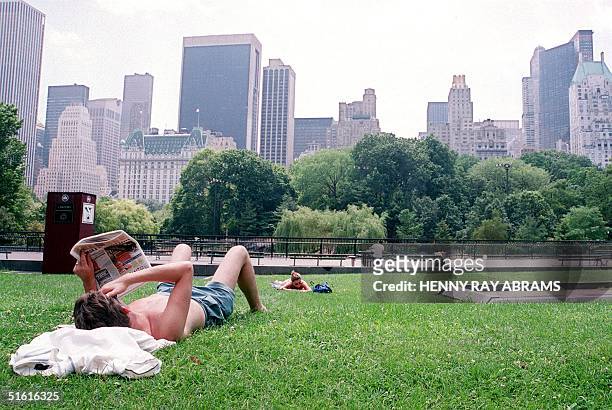 Man reads a newspaper as a heat wave continues in New York City 27 July, 1999 with temperatures in the mid-90's contributing to what may turn out to...