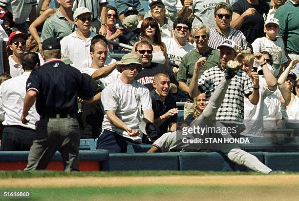 Third baseman Tony Fernandez of the Toronto Blue Jays dives into a field level box after making catch in foul territory of ball hit by Jorge Posada...