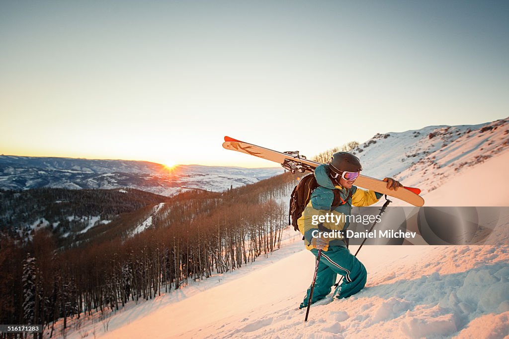 Guy with skis hiking during sunset in Colorado.