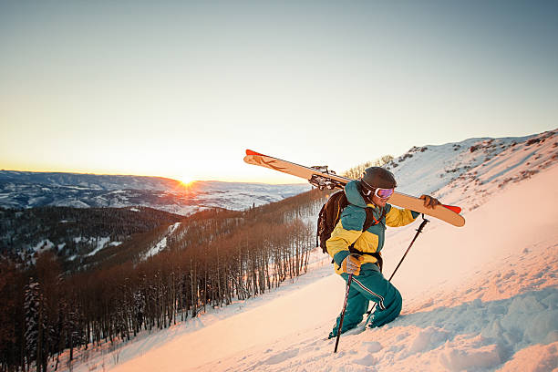 guy with skis hiking during sunset in colorado
