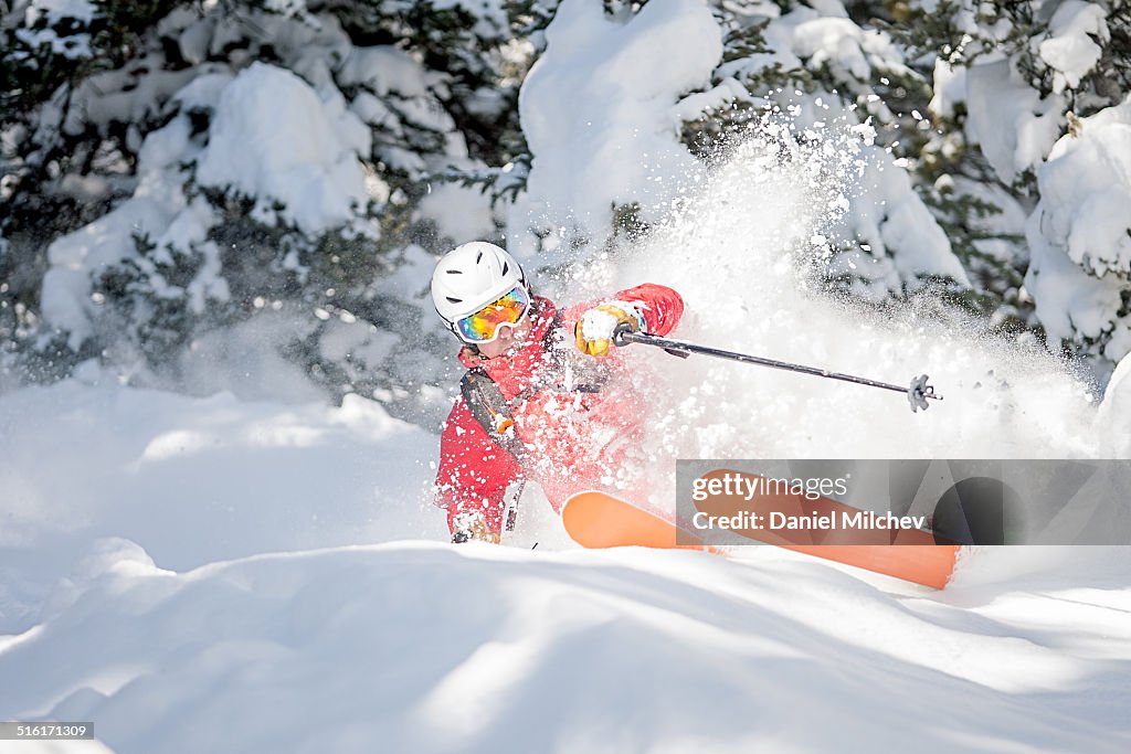 Skier slashing a turn in deep snow.