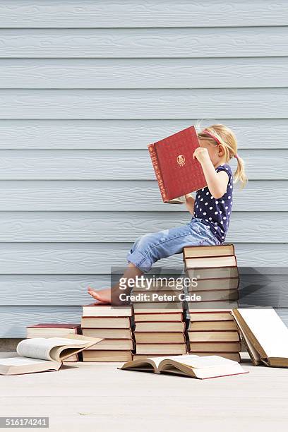 girl sitting on pile of books .girl reading book - open day 5 stockfoto's en -beelden