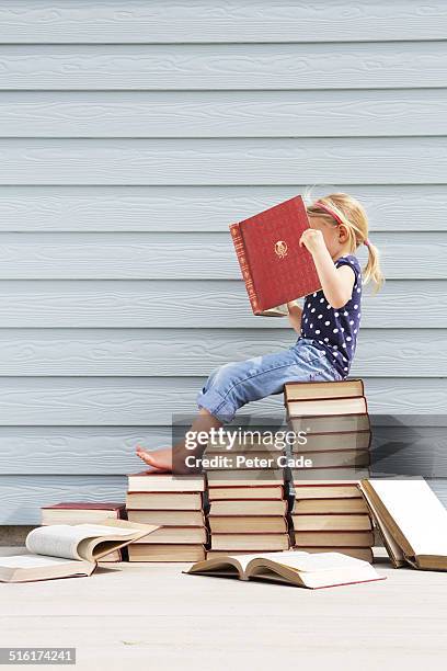 girl sitting on pile of books .girl reading book - heap stock pictures, royalty-free photos & images
